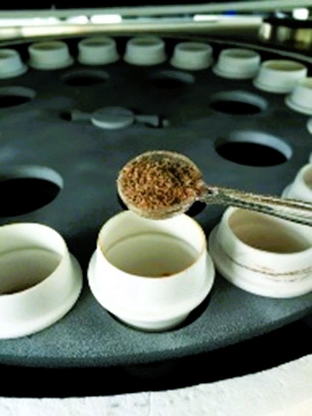 TGA801 system with ceramic turntable and crucibles. A rough mixture is being held in a spoon over the crucible.