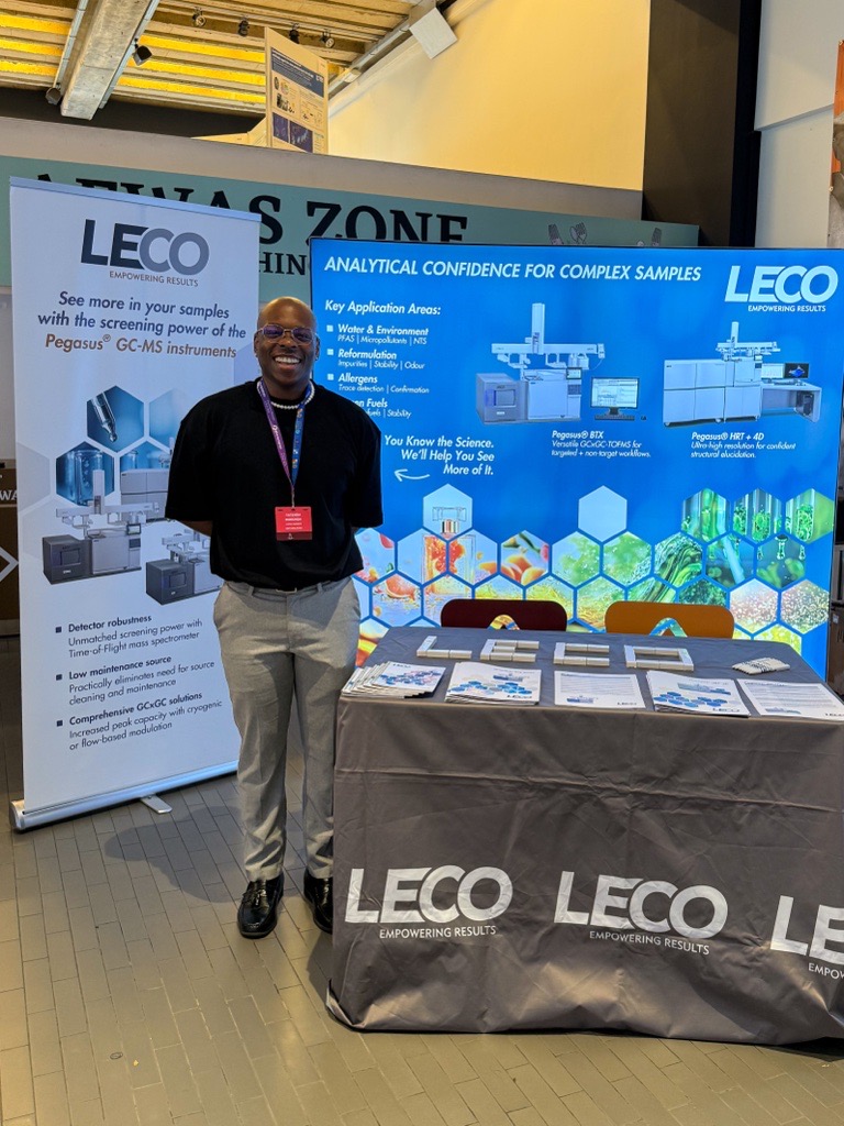 A LECO booth at a tradeshow is shown with a young man smiling at the camera.